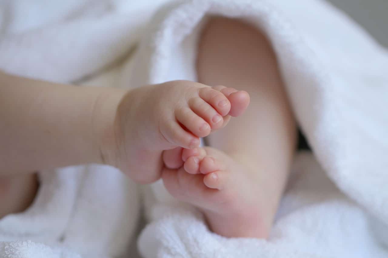 Les pieds d'un bébé qui est enroulé dans une serviette blanche.