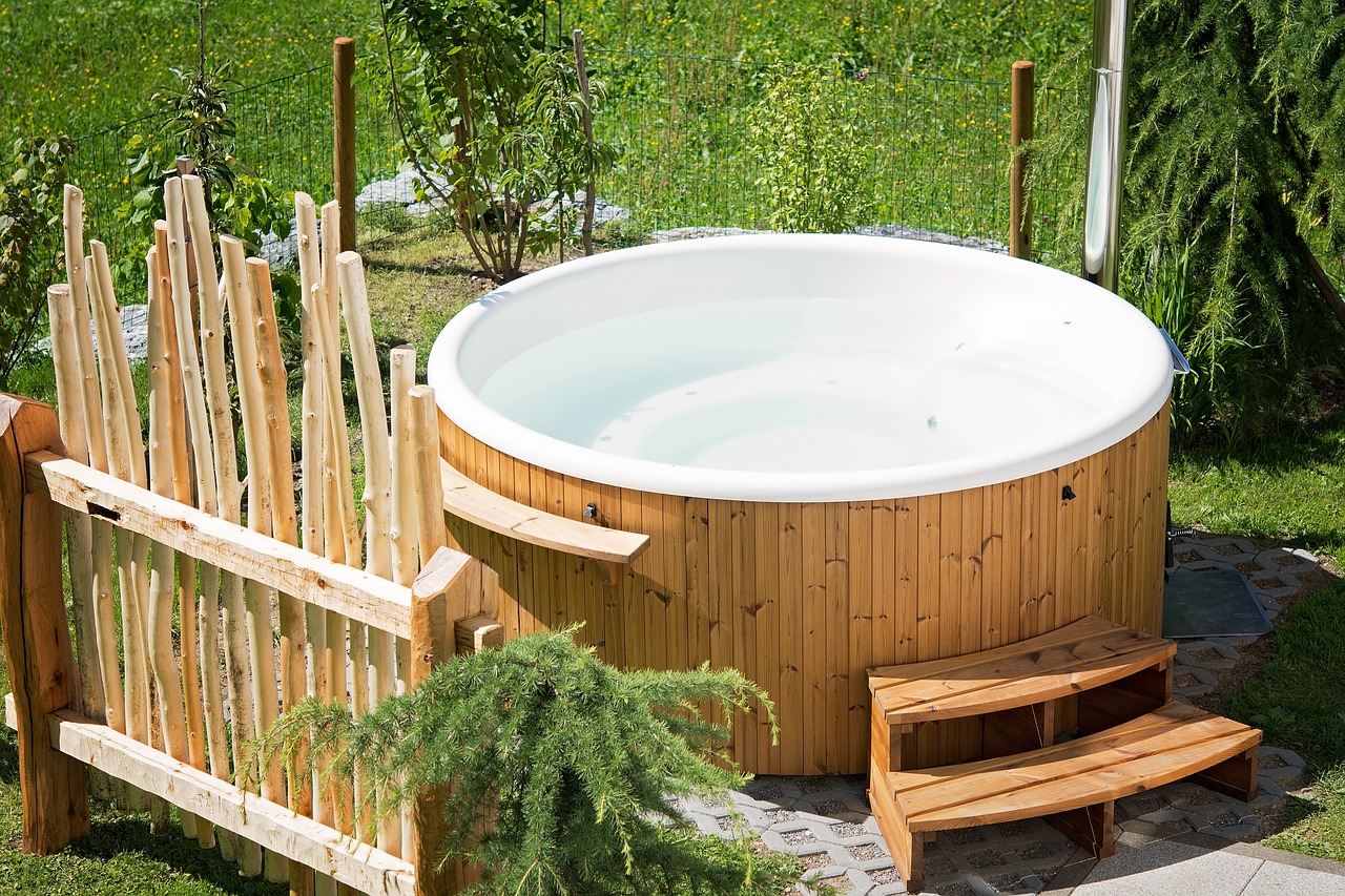 Un jacuzzi de bois en extérieur avec des arbres verts autour.